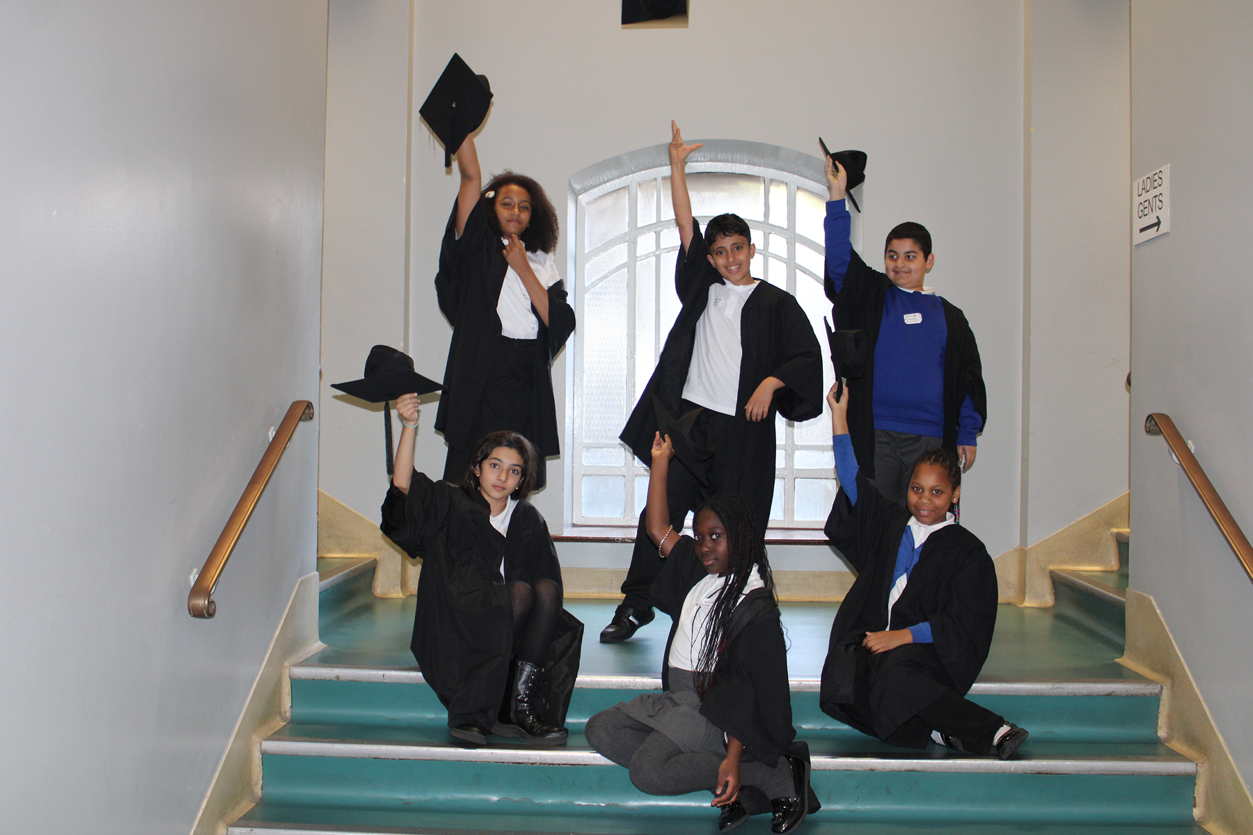 Six primary school children dress in graduation gowns