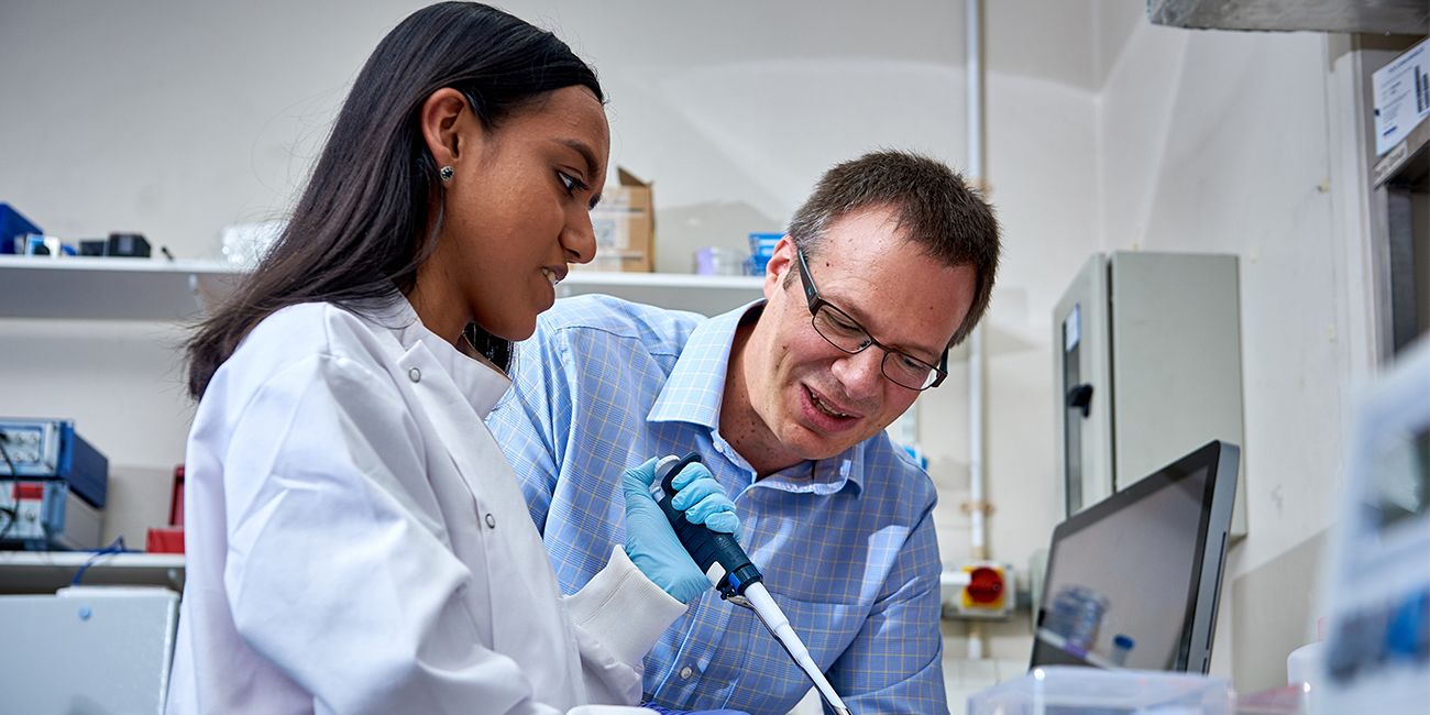 Two bioelectronics academics use a pipette.