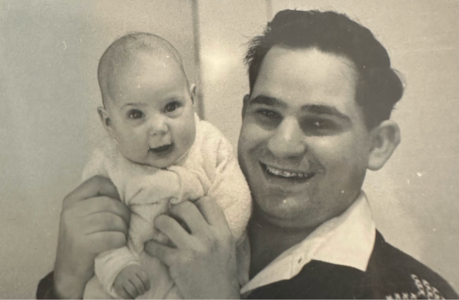 David holds a baby girl in his arms, both smiling