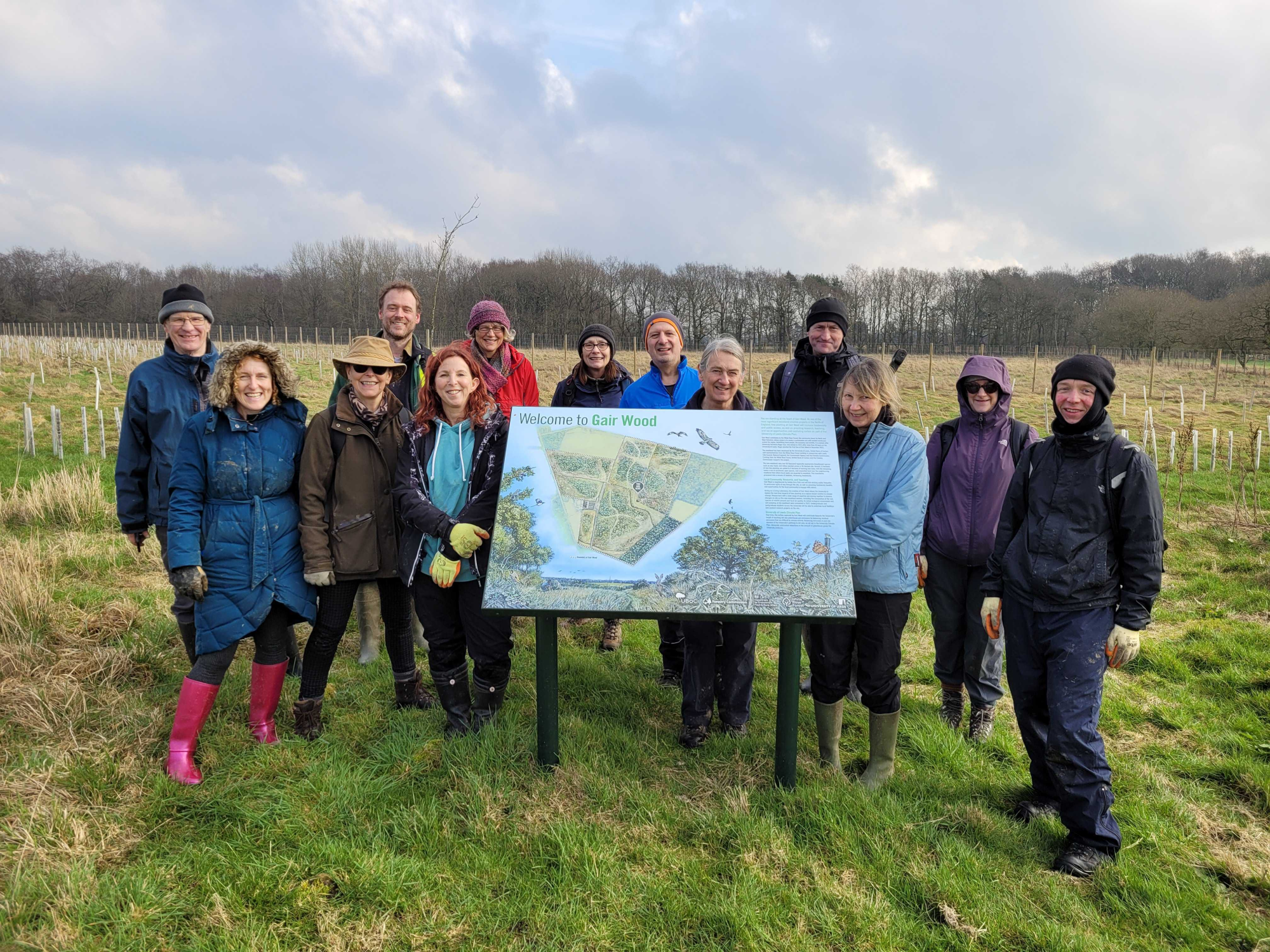 A group pose in the countryside behind a plaque