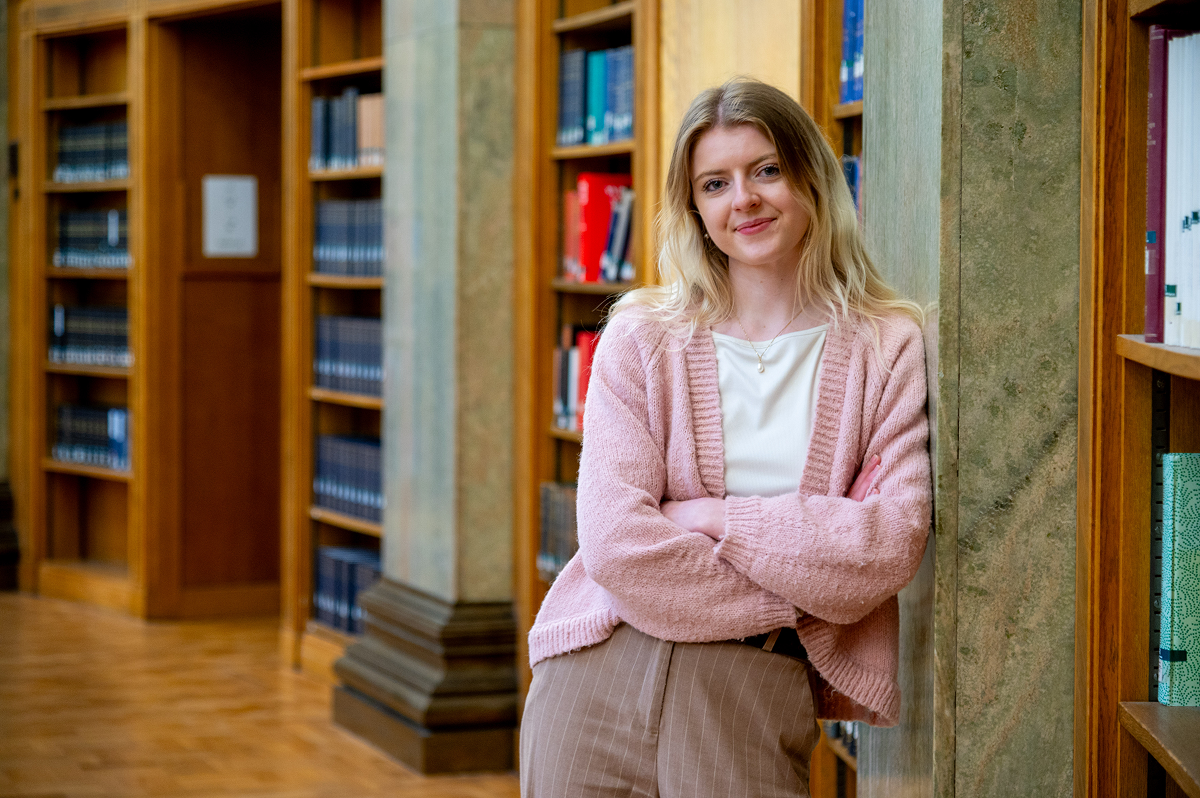 Eden leans against a pillar in the Brotherton Library