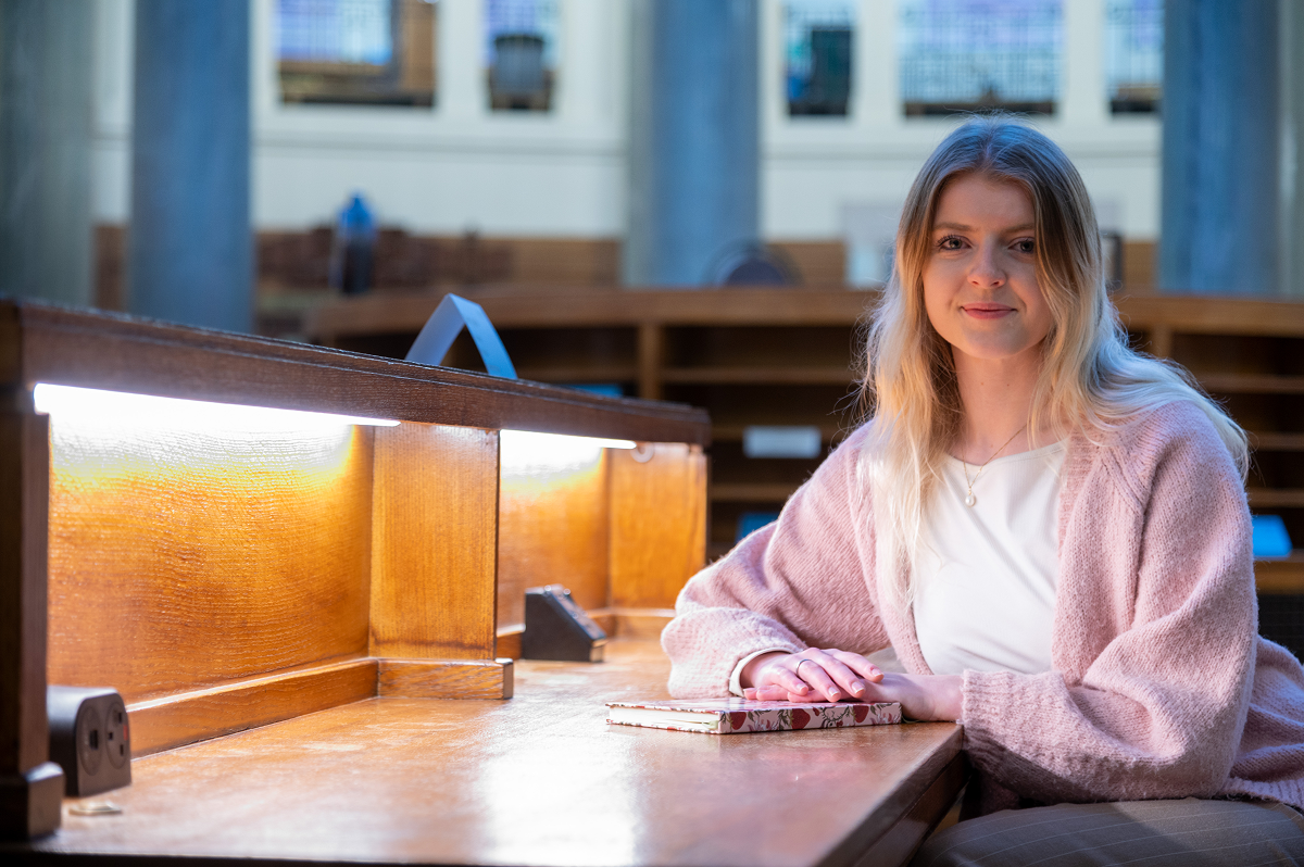 Eden Page sits at a desk in the Brotherton Library