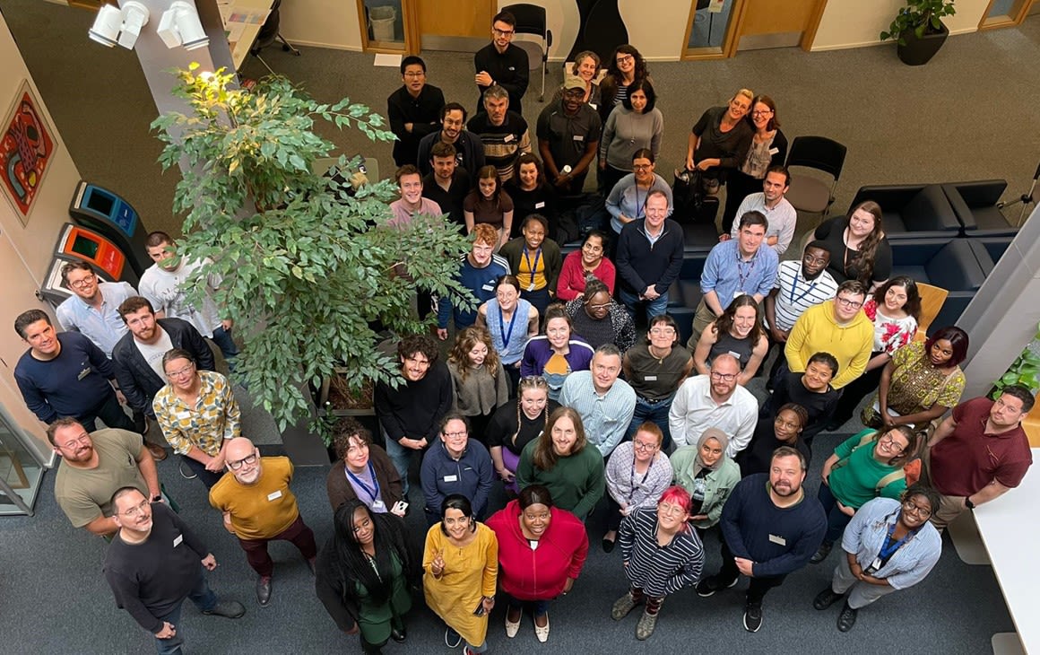large group of students gathered in a hall smiling upwards at the camera.