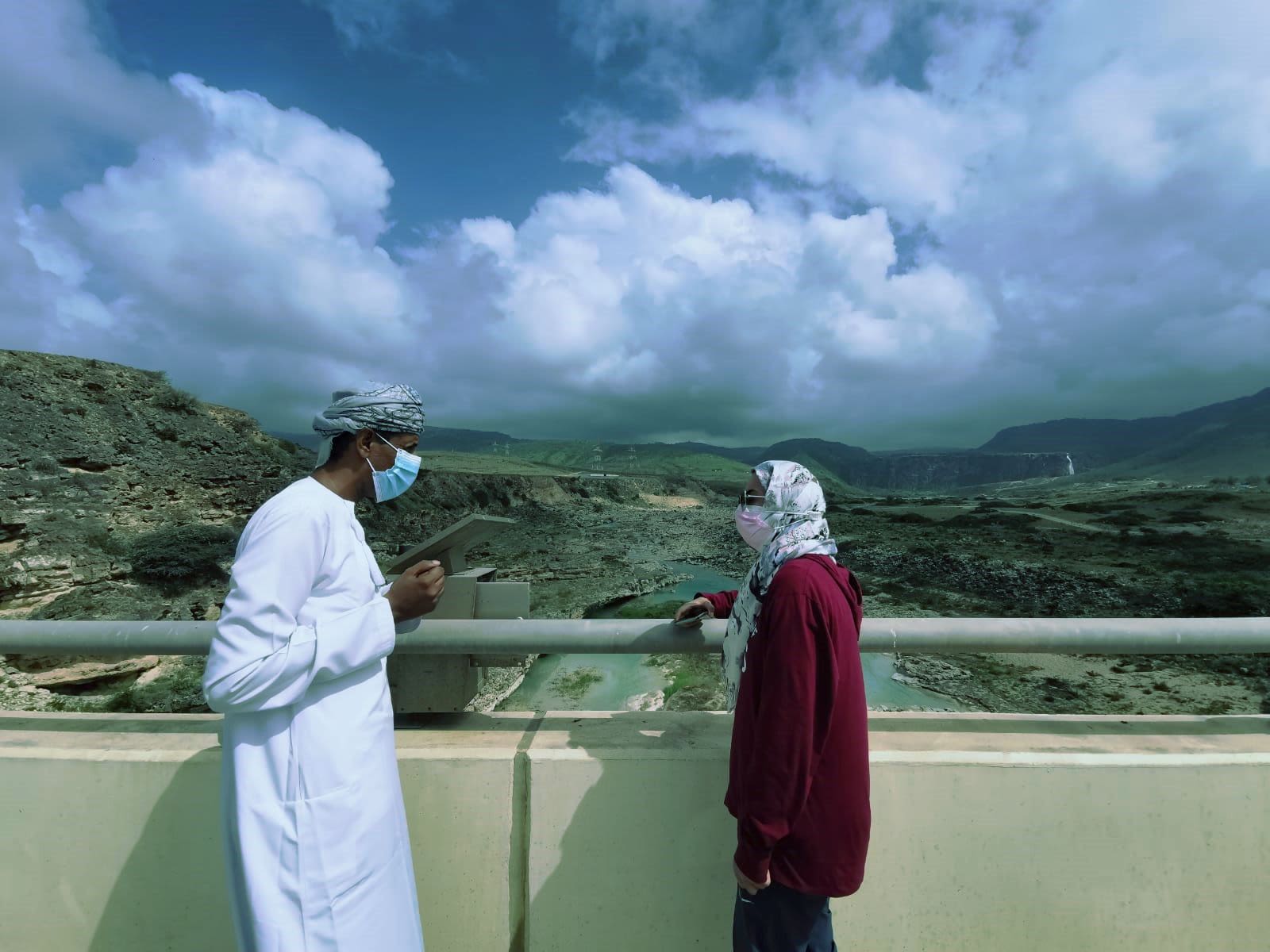 two people discuss water research beside a water installation in Dhohar.
