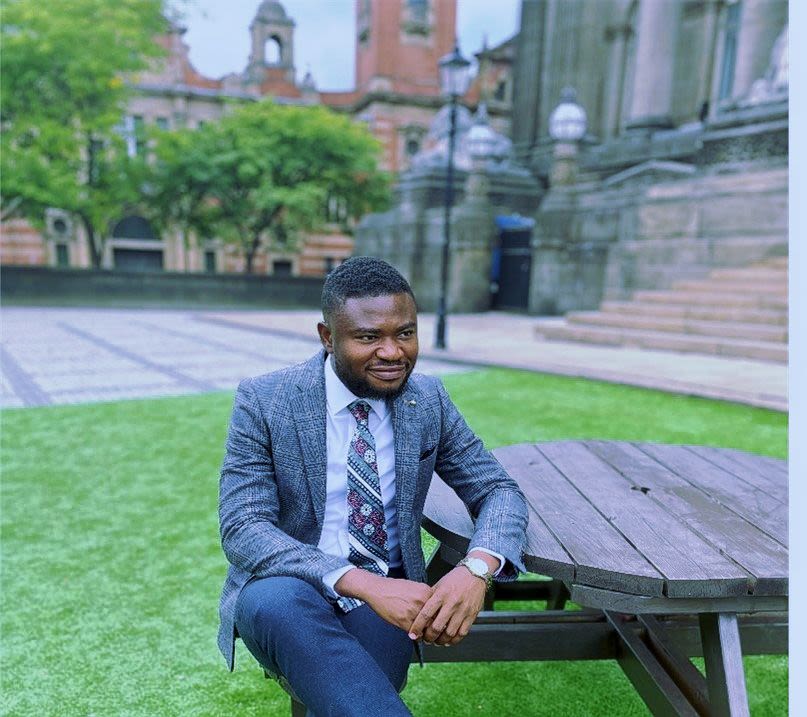 Murat Okumah seated at a bench on University campus
