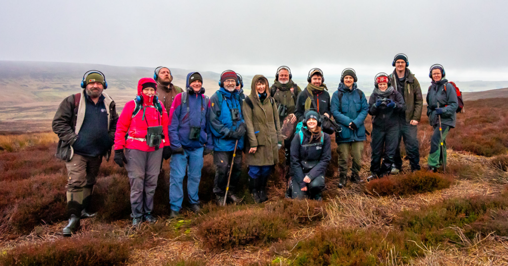 group of walkers on moorside wearing headphones