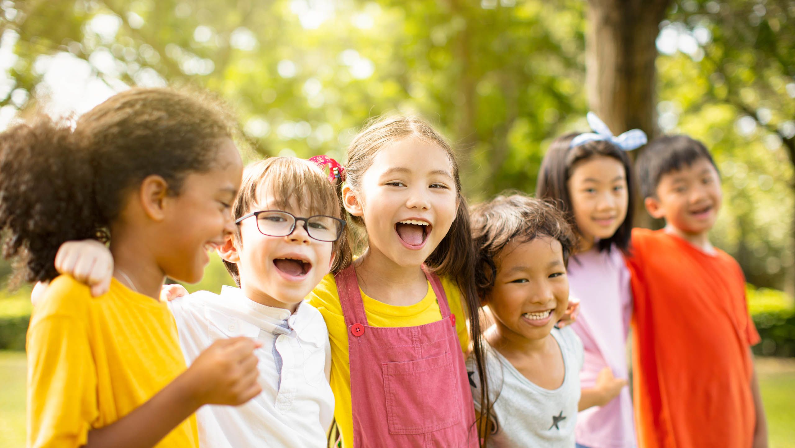 A group of children standing in a line with their arms around each other's shoulders