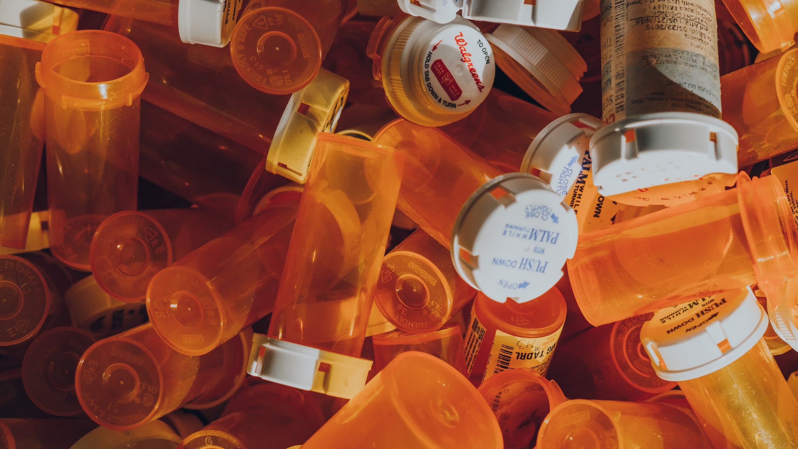 A pile of empty orange plastic medicine bottles