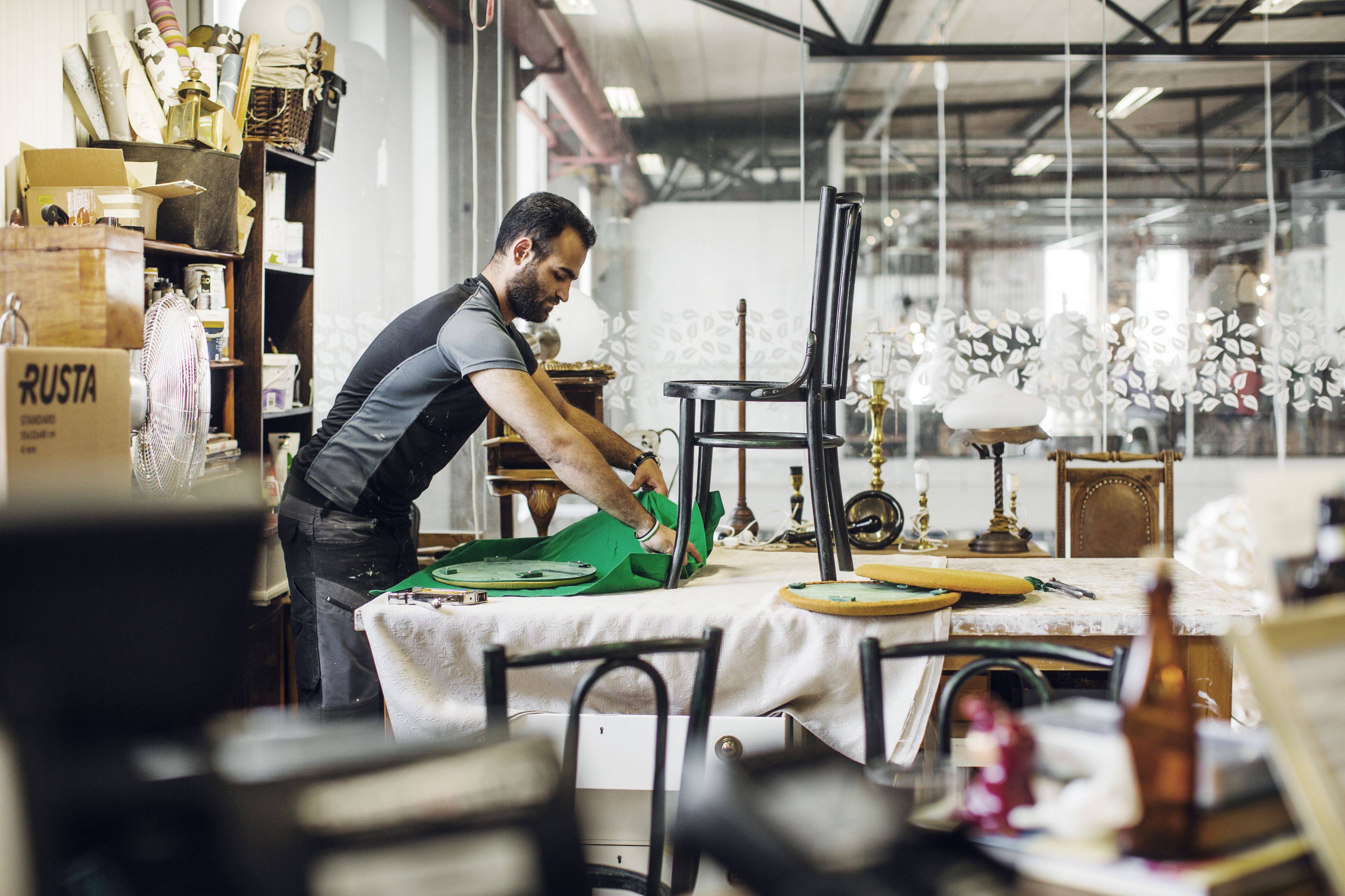A man recovering a chair with new material.
