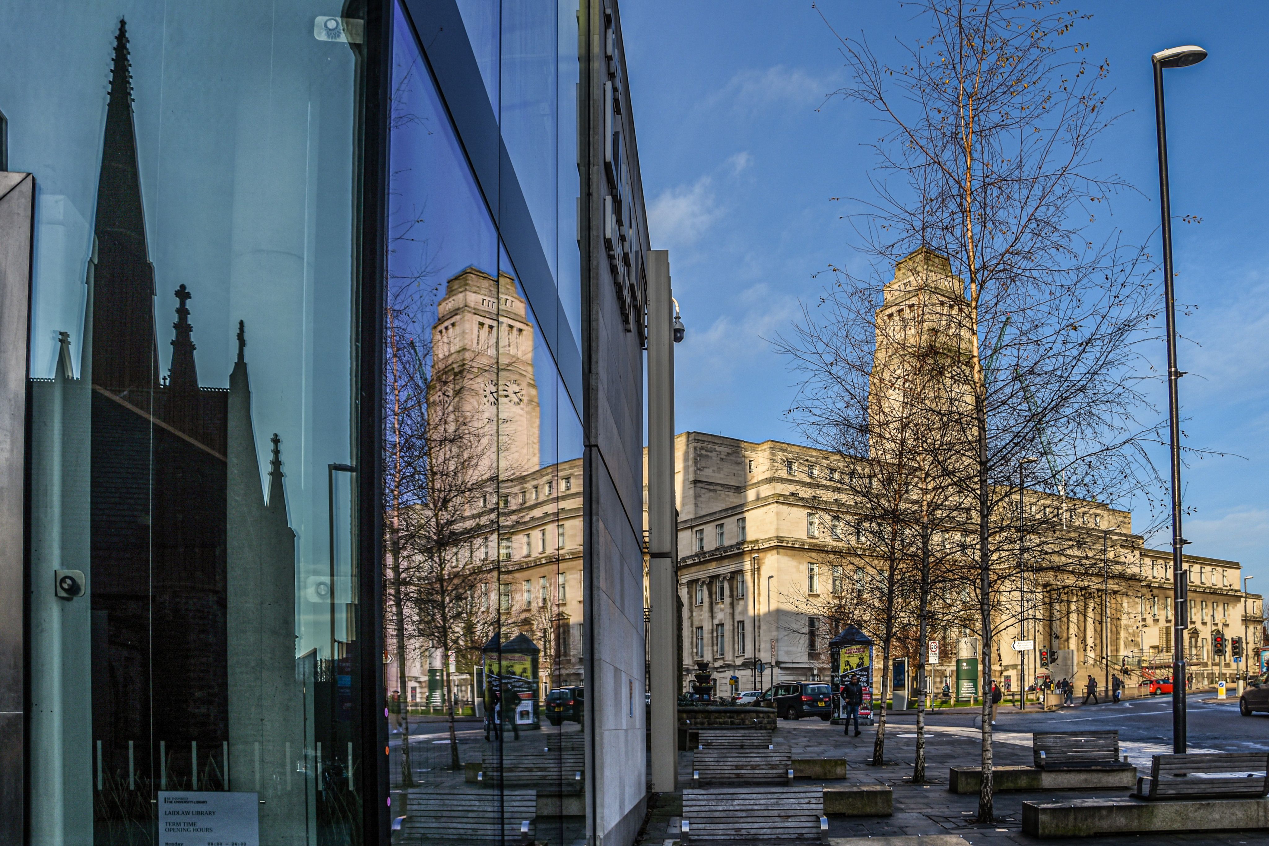 The University of Leeds Parkinson Building on a bright winter's day. In the foreground, a building with a glass front is reflecting the image of the Parkinson Tower