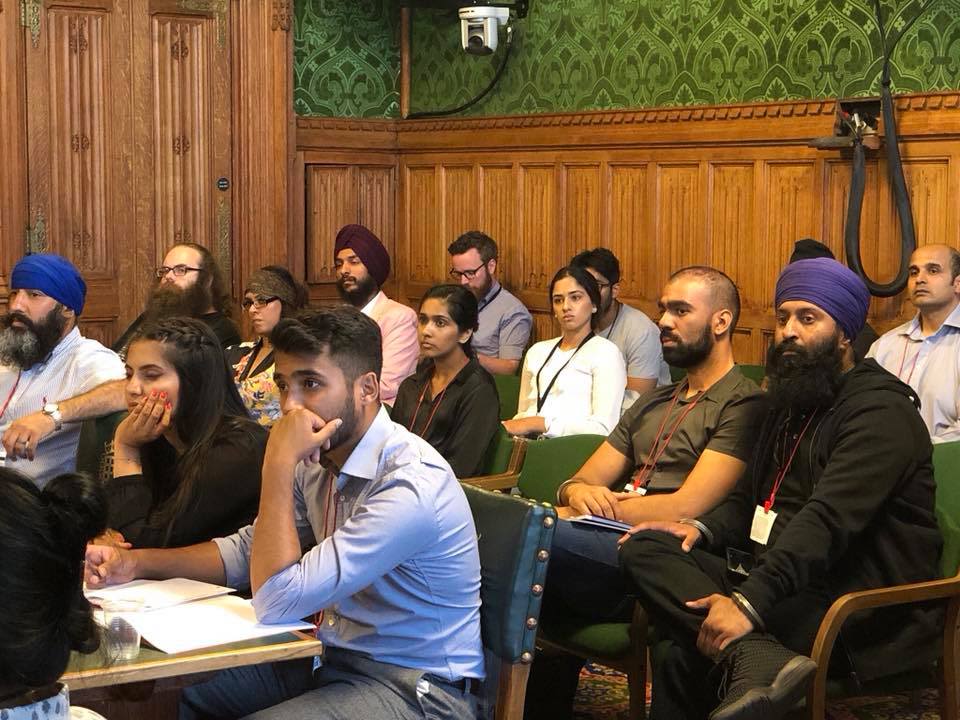 A group of people sat in a wood-panelled room looking at something taking place off camera