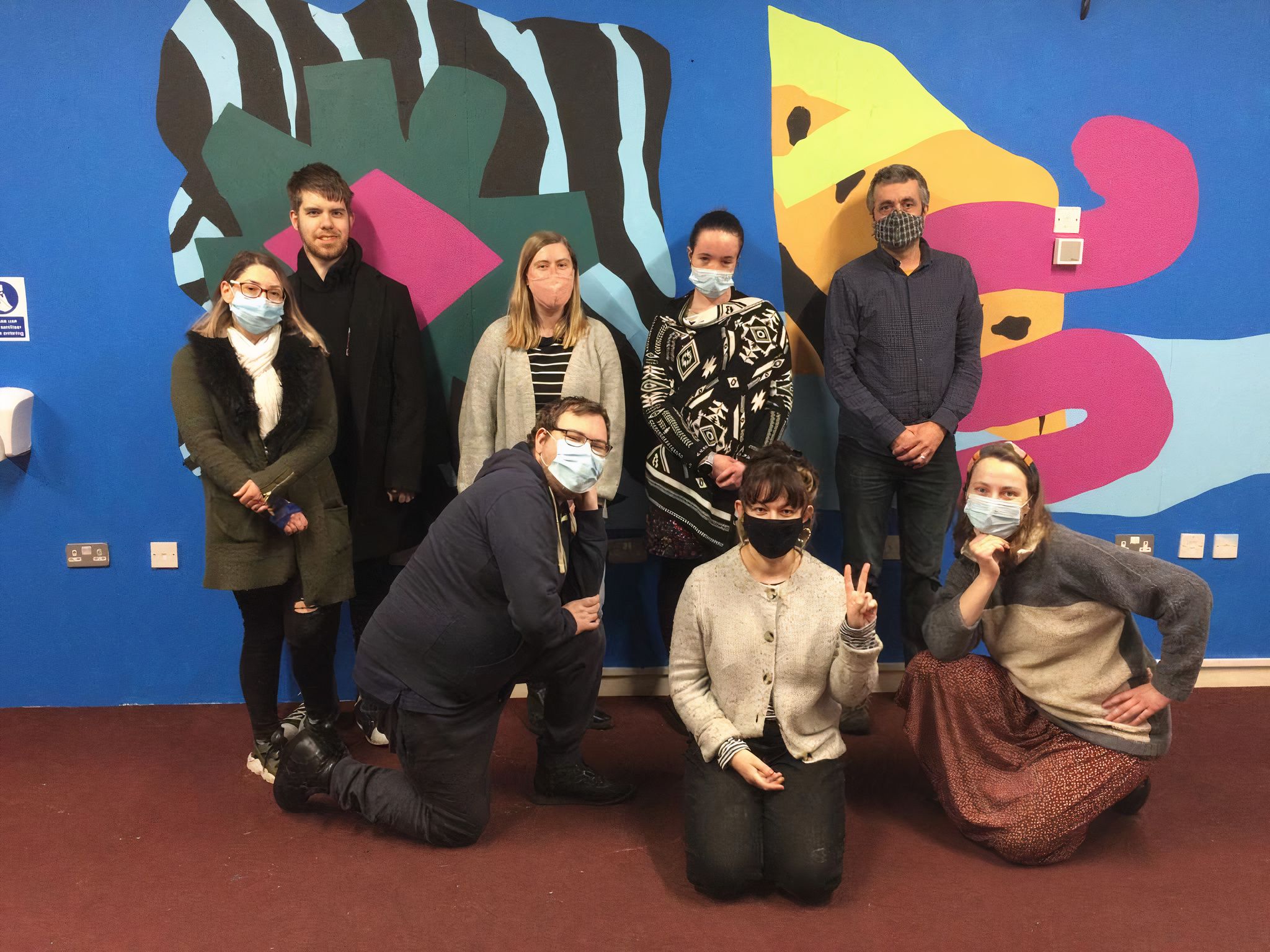 The Pyramid Arts Team stood before a wall featuring artwork.