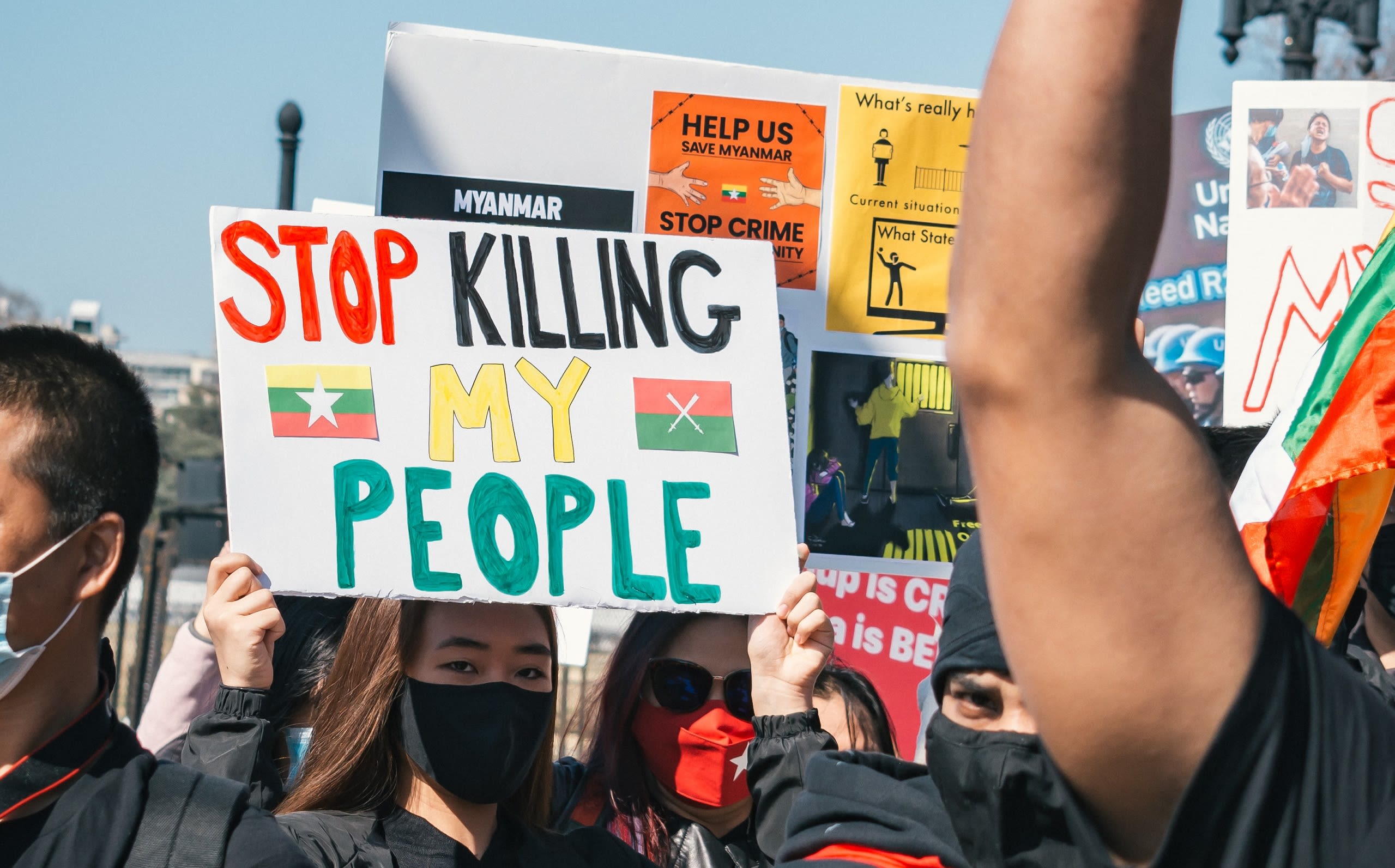 Protestor in a crowd in Myanmar holding a sign that says 'Stop killing my people'.