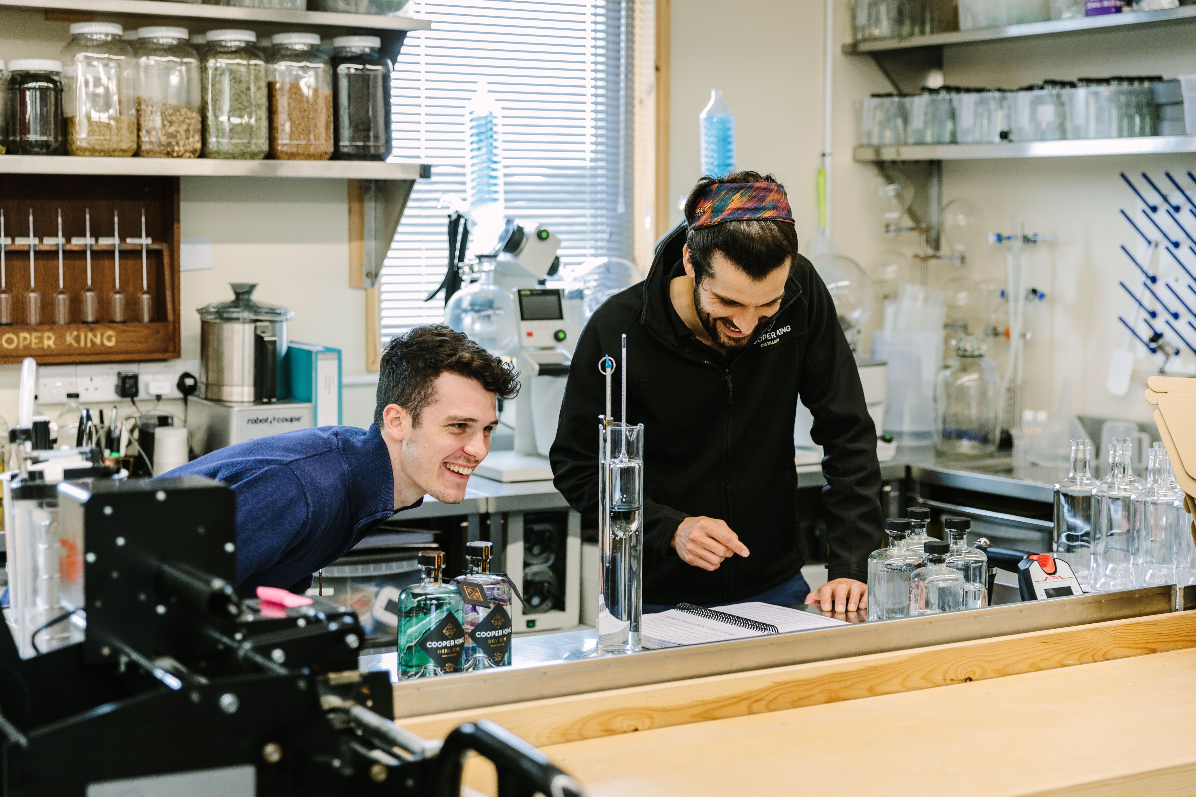 A student working with York-based gin and whisky distillery. A student is working in a laboratory with chemicials and an enterprise partner is reviewing notes from the experiment.