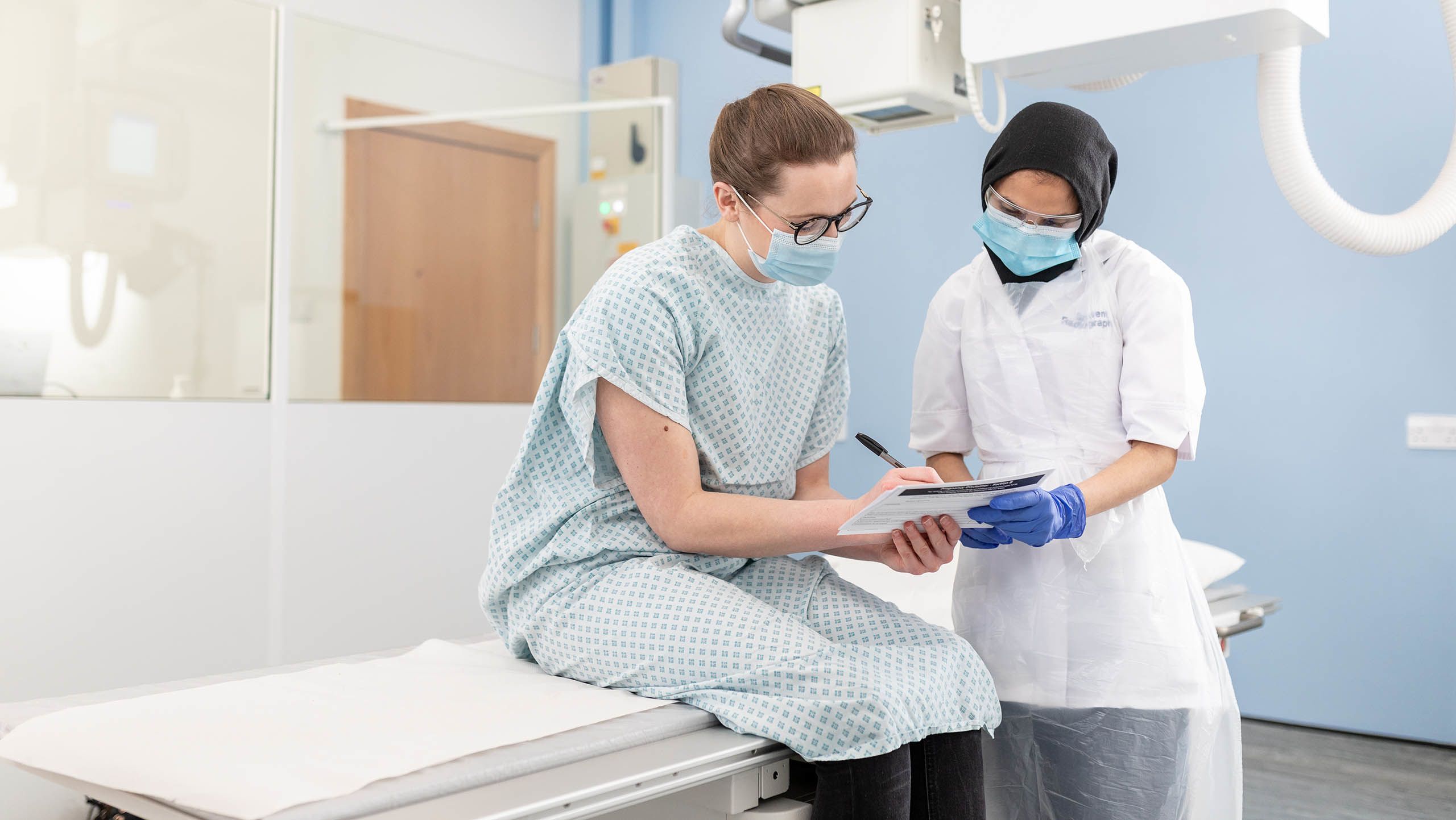 A radiography student and a patient signing a document in a hospital