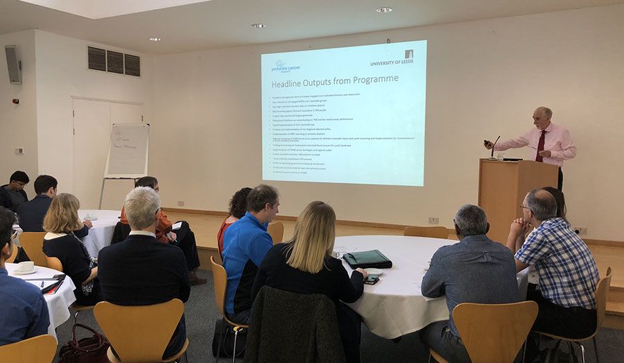 Simon Howell presenting to a group of people from a lecturn at the front of a conference room