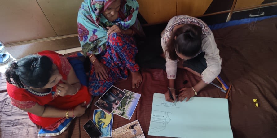 Three people seen from overhead drawing out diagrams on a large piece of paper.